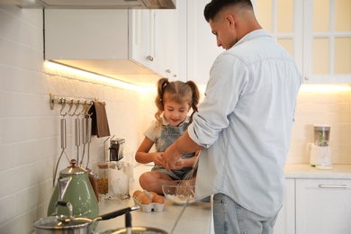 Photo of Little girl with her father cooking together in modern kitchen