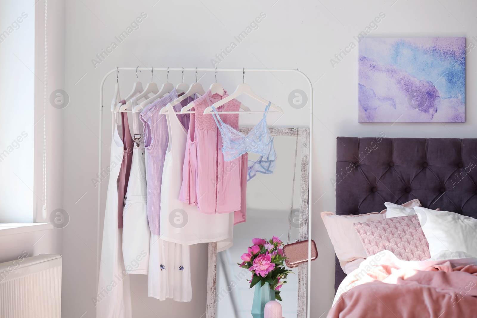 Photo of Stylish bedroom interior with clothes rack and mirror