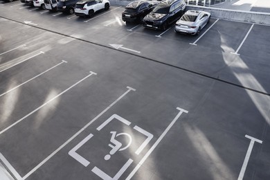 Image of Car parking lot with white marking lines and wheelchair symbol outdoors, above view