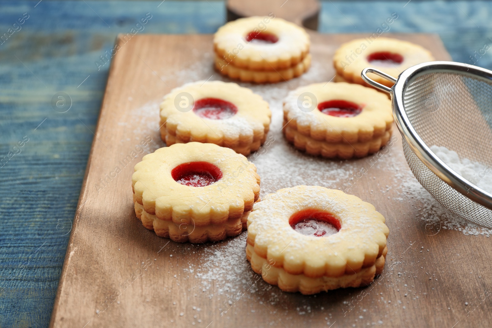 Photo of Traditional Christmas Linzer cookies with sweet jam and sugar powder on wooden board