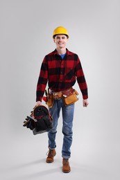 Professional repairman with tool box on light grey background