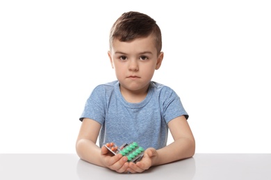 Little child with different pills on white background. Household danger