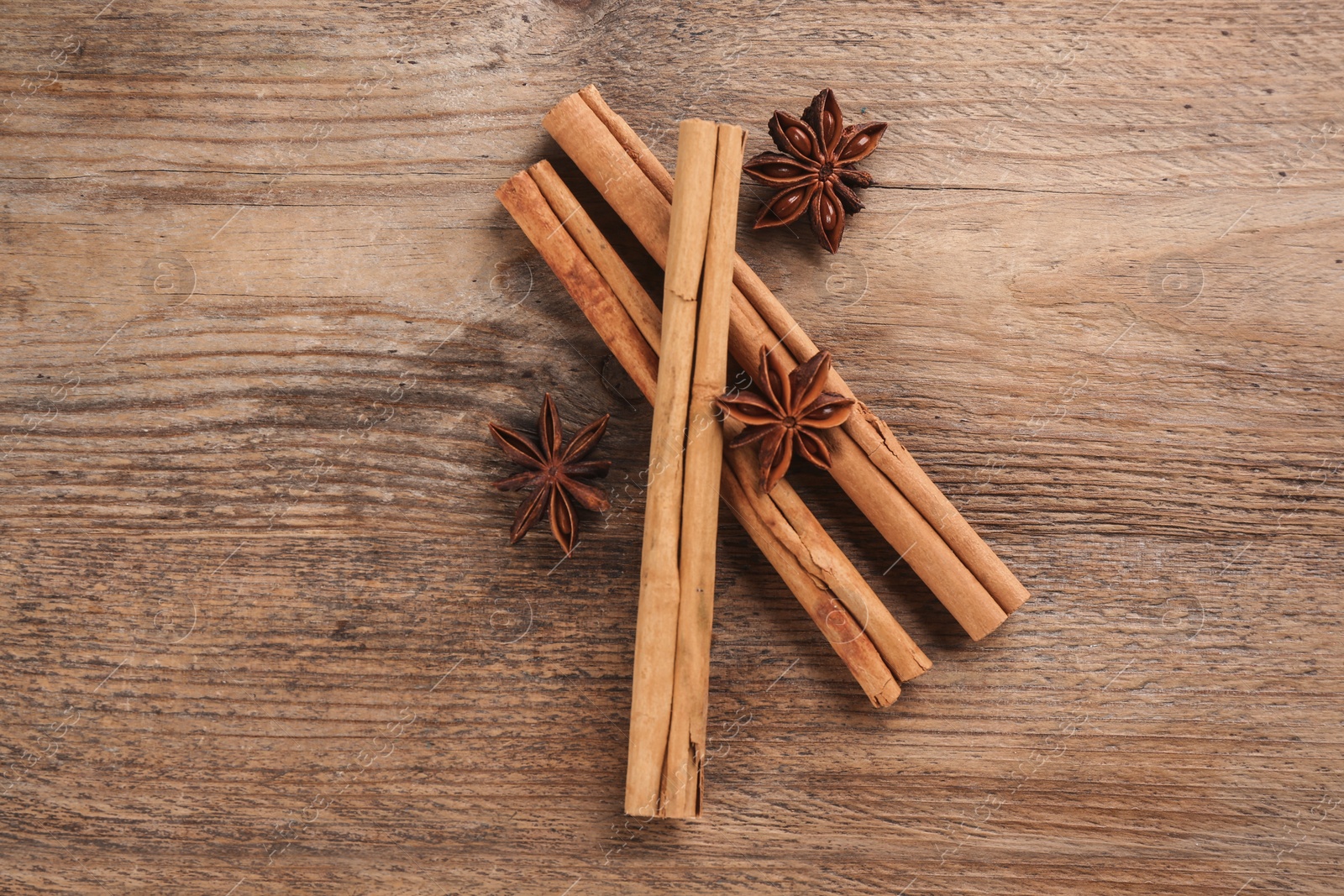 Photo of Aromatic cinnamon sticks and anise on wooden table, flat lay