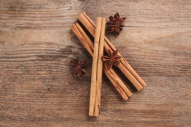 Photo of Aromatic cinnamon sticks and anise on wooden table, flat lay