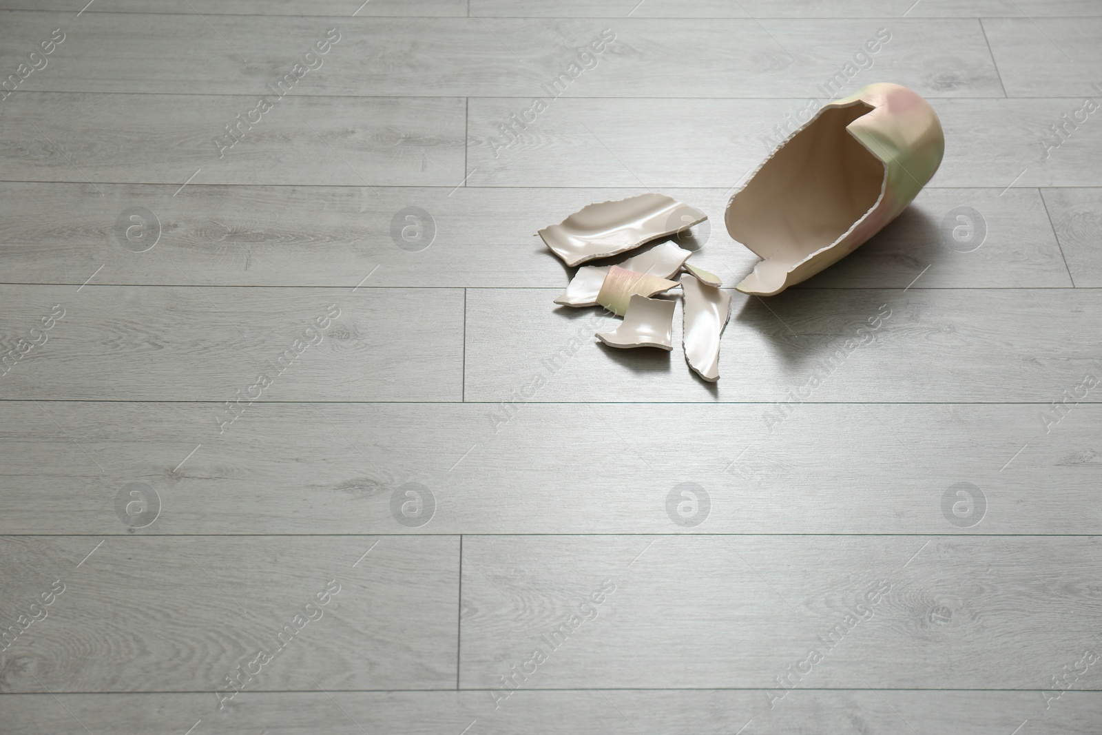 Photo of Broken ceramic vase on wooden floor. Space for text