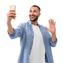 Smiling young man taking selfie with smartphone on white background