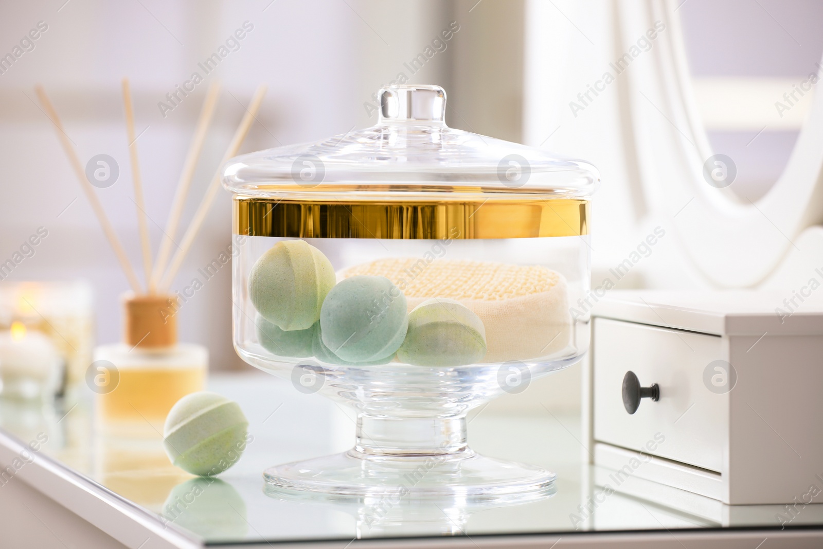Photo of Jar with bath bombs and bath sponge on dressing table indoors