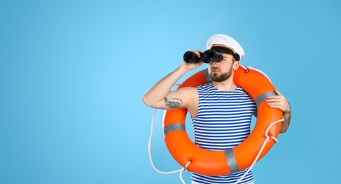 Photo of Sailor with binoculars and ring buoy on light blue background