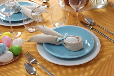 Photo of Festive table setting with painted eggs, plate and cutlery. Easter celebration