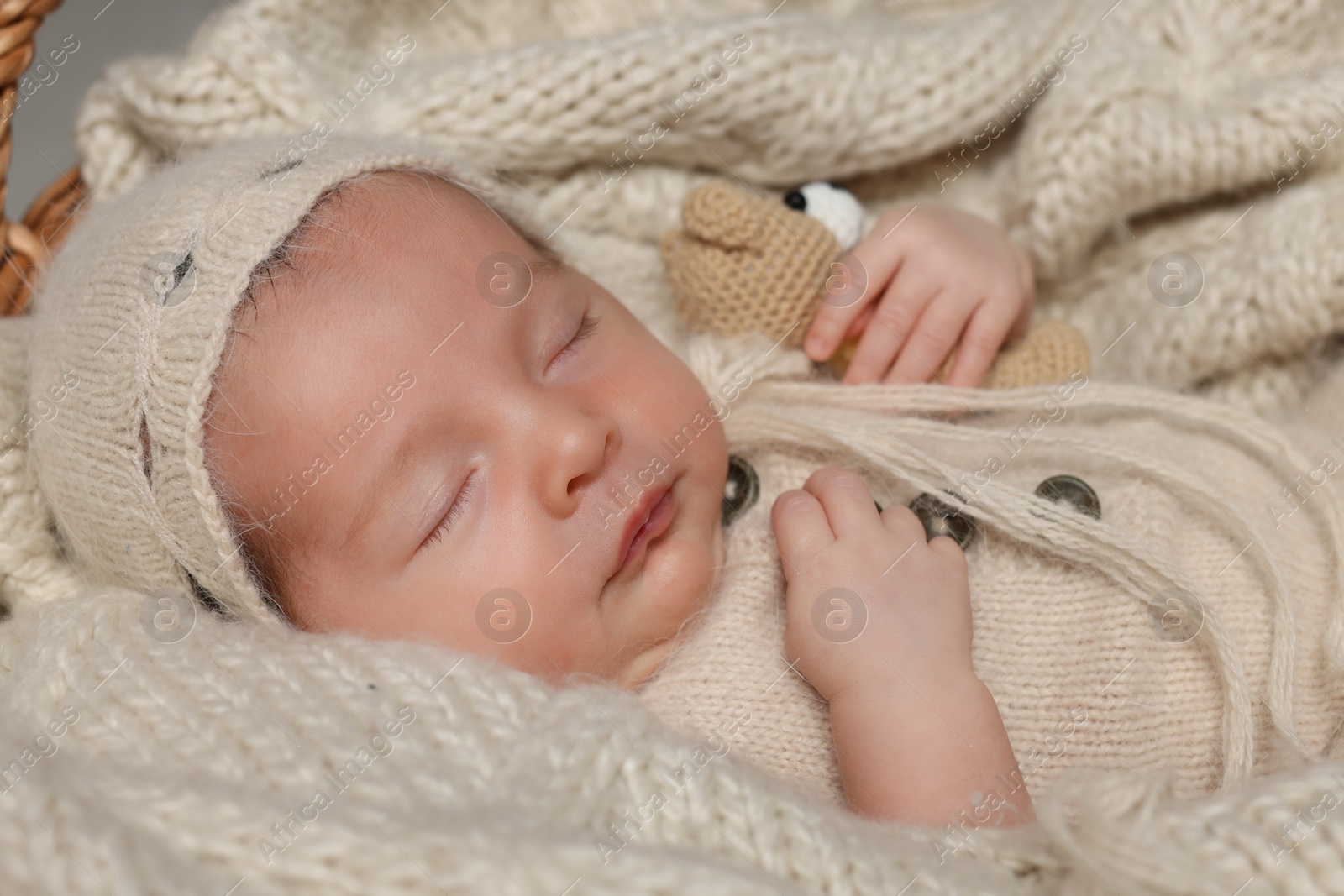 Photo of Adorable newborn baby with toy bear sleeping on knitted plaid, closeup