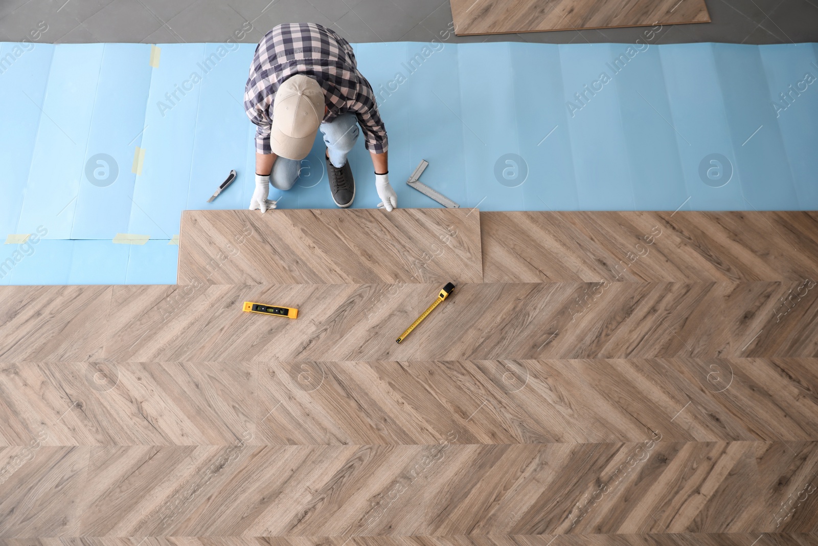 Photo of Worker installing laminated wooden floor indoors, above view