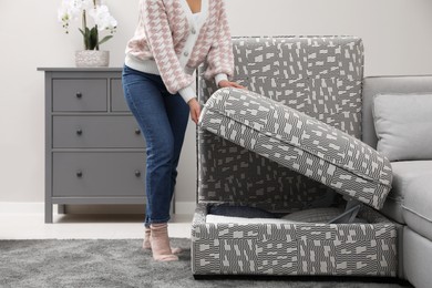 Photo of Woman closing modular sofa section with storage in living room, closeup
