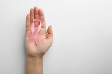 Woman holding pink ribbon on white background, top view with space for text. Breast cancer awareness concept