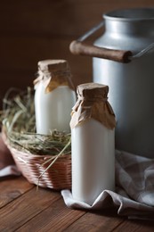 Photo of Tasty fresh milk in can and bottles on wooden table