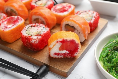 Photo of Different delicious sushi rolls on white marble table, closeup