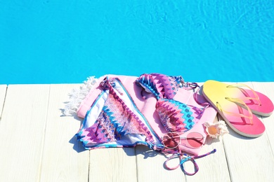 Photo of Beach accessories on wooden deck near swimming pool. Space for text