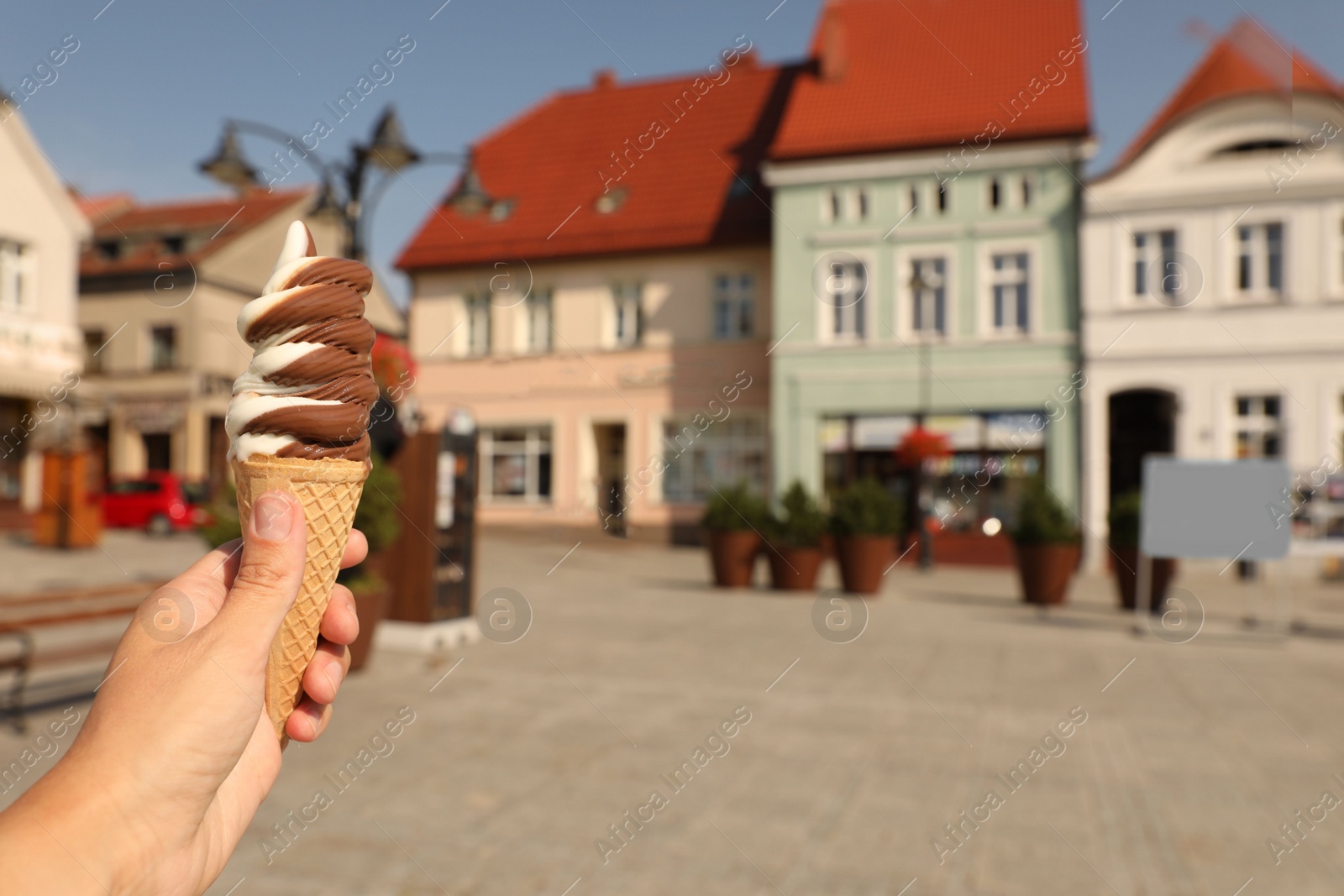 Photo of Woman holding delicious ice cream in wafer cone outdoors, closeup. Space for text