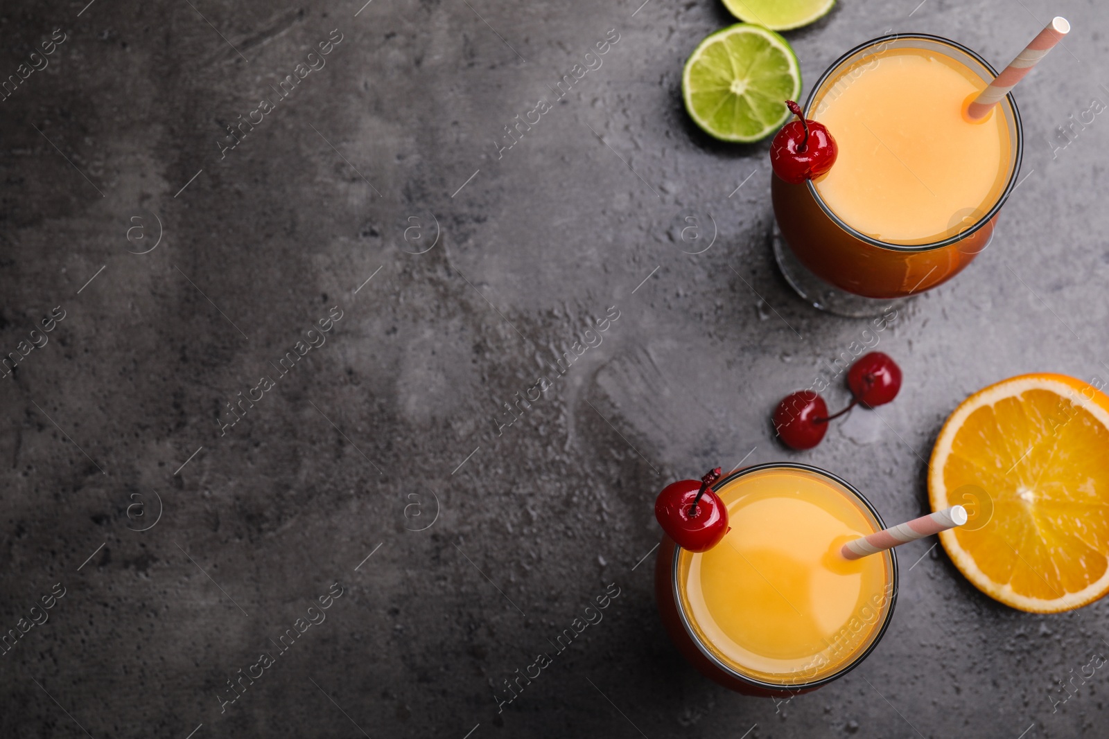 Photo of Fresh alcoholic Tequila Sunrise cocktails on grey table, flat lay. Space for text