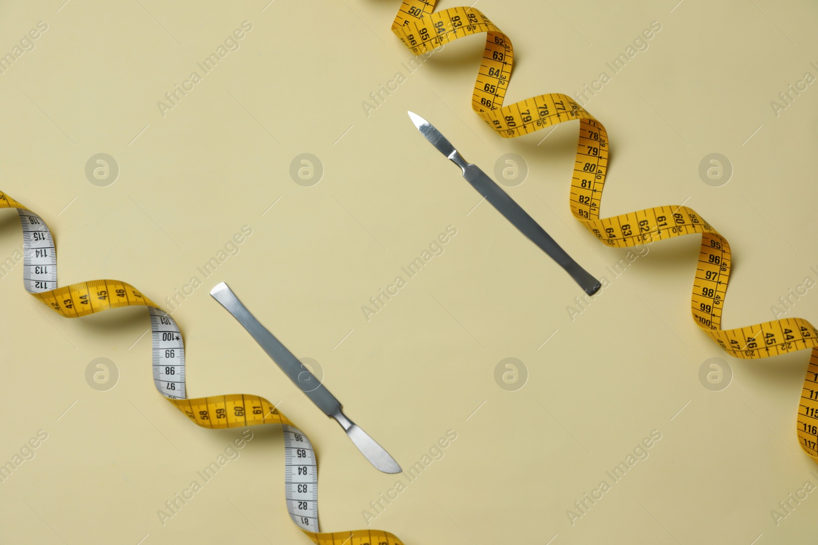 Photo of Scalpels and measuring tape on beige background, flat lay with space for text. Weight loss surgery