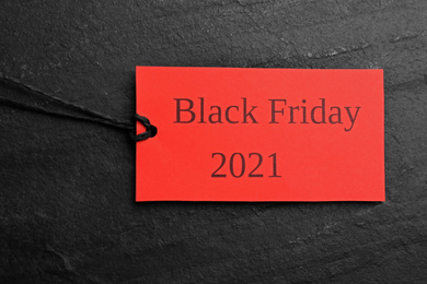 Red tag with words BLACK FRIDAY 2021 on dark slate background, top view