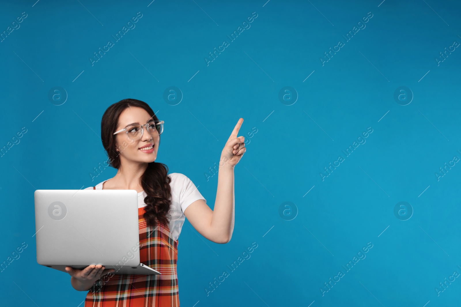 Photo of Young woman with laptop on blue background. Space for text