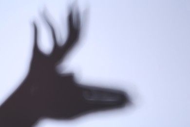 Photo of Shadow of hands like deer on light background. Space for text