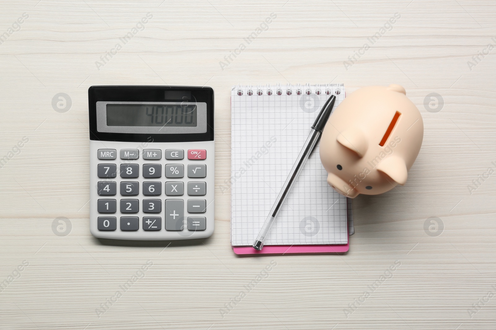 Photo of Calculator, piggy bank, notebook and pen on white wooden table, flat lay