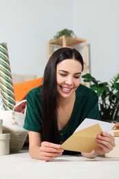 Photo of Happy woman reading greeting card on floor in living room