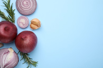 Fresh red onions, garlic and rosemary on light blue background, flat lay. Space for text