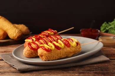 Delicious corn dogs with mustard and ketchup on wooden table