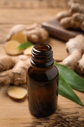 Glass bottle of essential oil and ginger root on wooden table