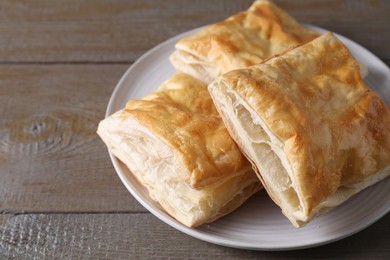 Photo of Delicious fresh puff pastries on wooden table, closeup. Space for text