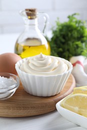 Photo of Fresh mayonnaise sauce in bowl and ingredients on table