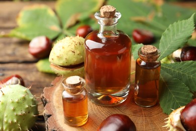 Chestnuts and bottles of essential oil on wooden table, closeup