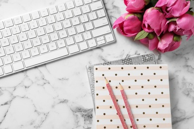 Stylish workplace with fragrant peonies on marble table, flat lay. Space for text