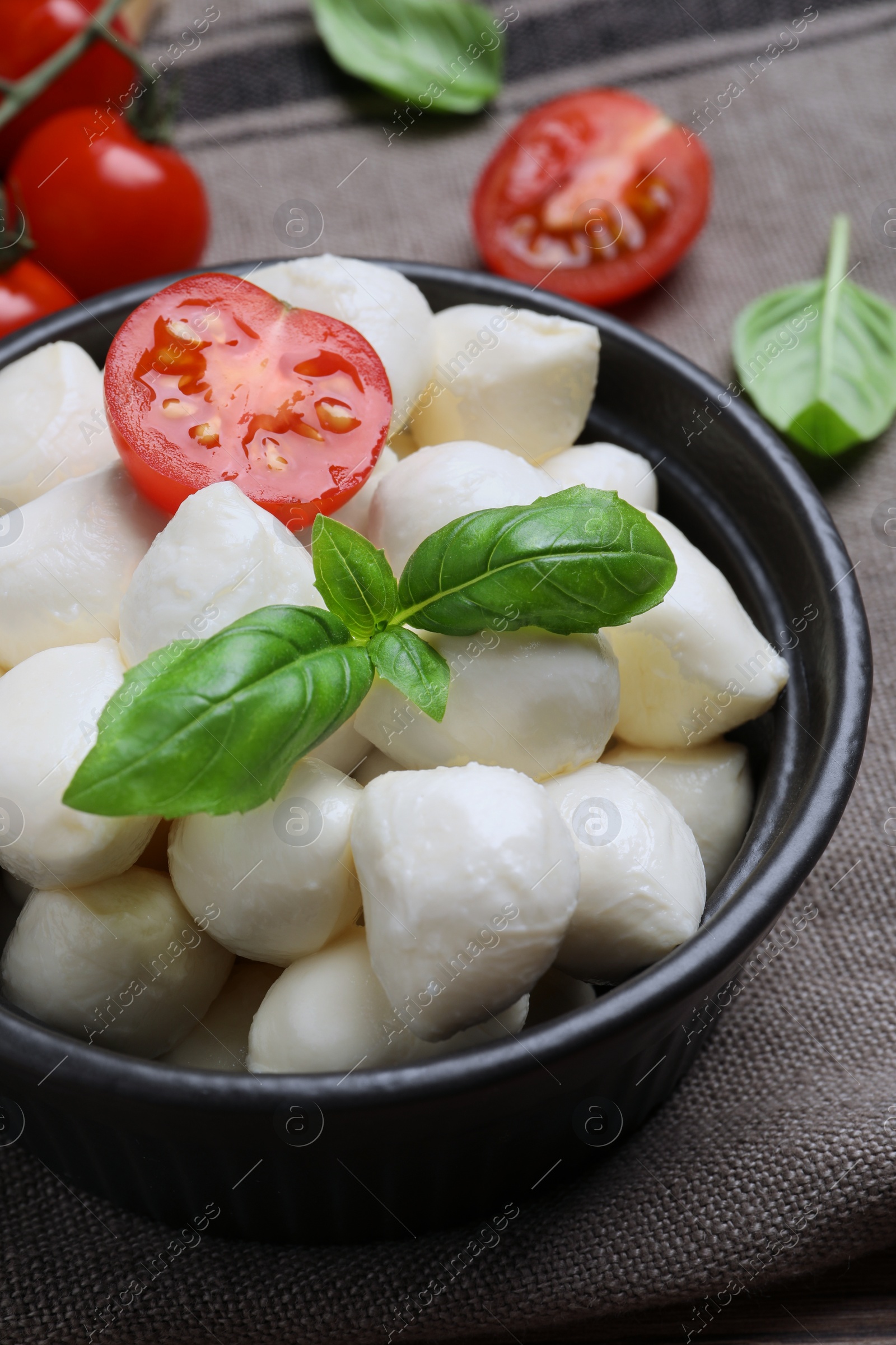 Photo of Delicious mozzarella balls, tomatoes and basil leaves on table, closeup