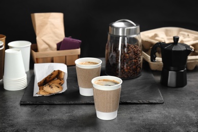 Photo of Composition with aromatic hot coffee in paper cups and cookies on table