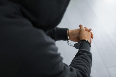 Photo of Man detained in handcuffs indoors, closeup view. Criminal law