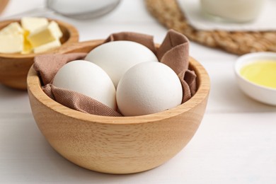 Photo of Bowl with eggs on white wooden table, closeup. Ingredients for crepes