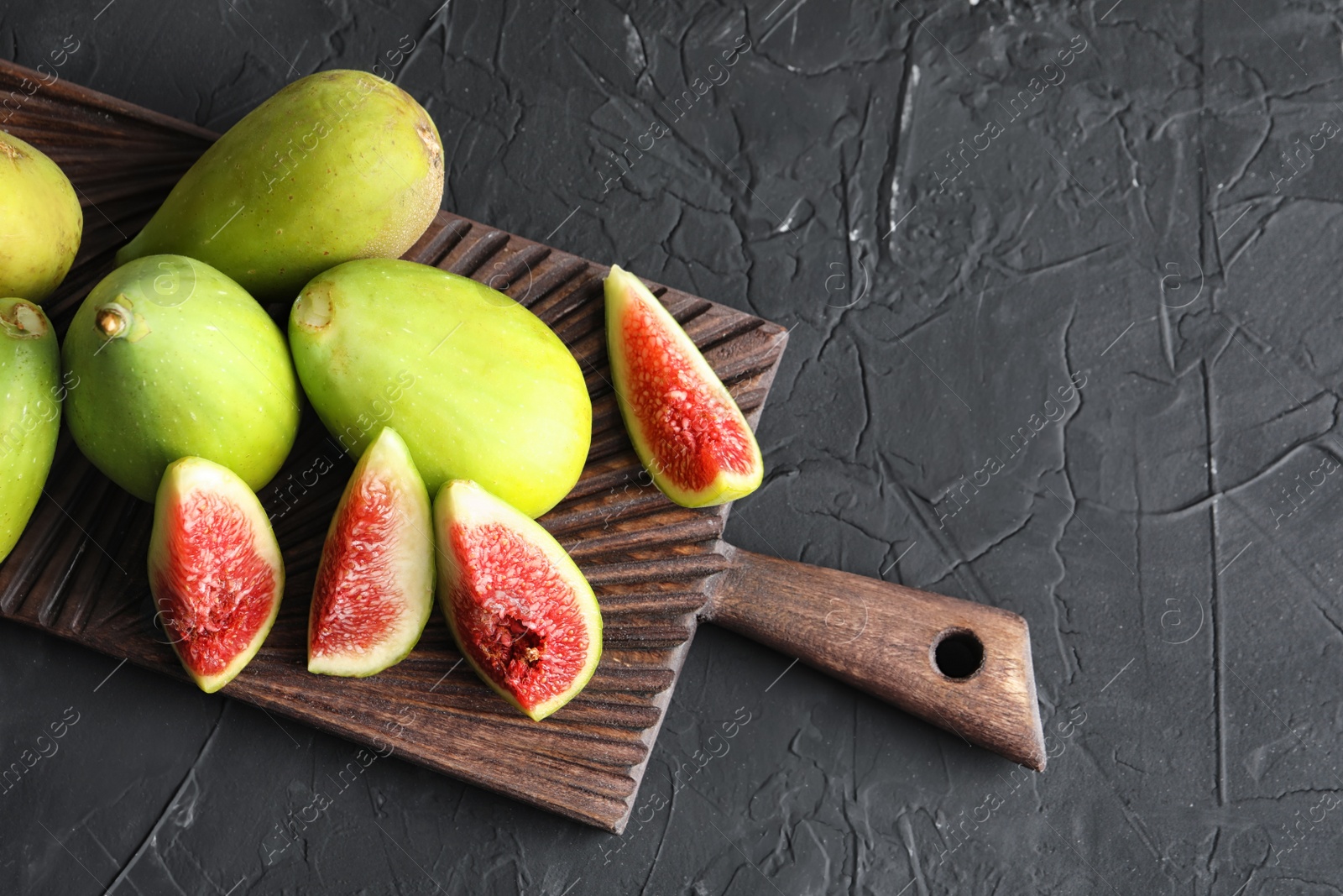 Photo of Cutting board with fresh ripe figs on dark background, top view