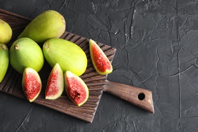 Cutting board with fresh ripe figs on dark background, top view