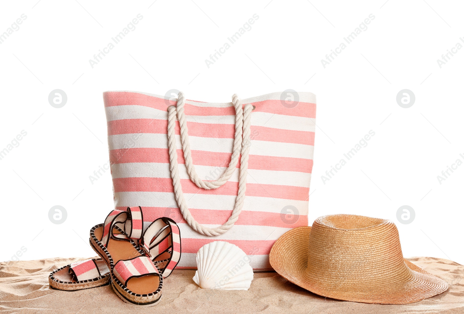 Photo of Stylish striped bag and beach accessories on sand against white background