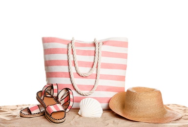 Photo of Stylish striped bag and beach accessories on sand against white background