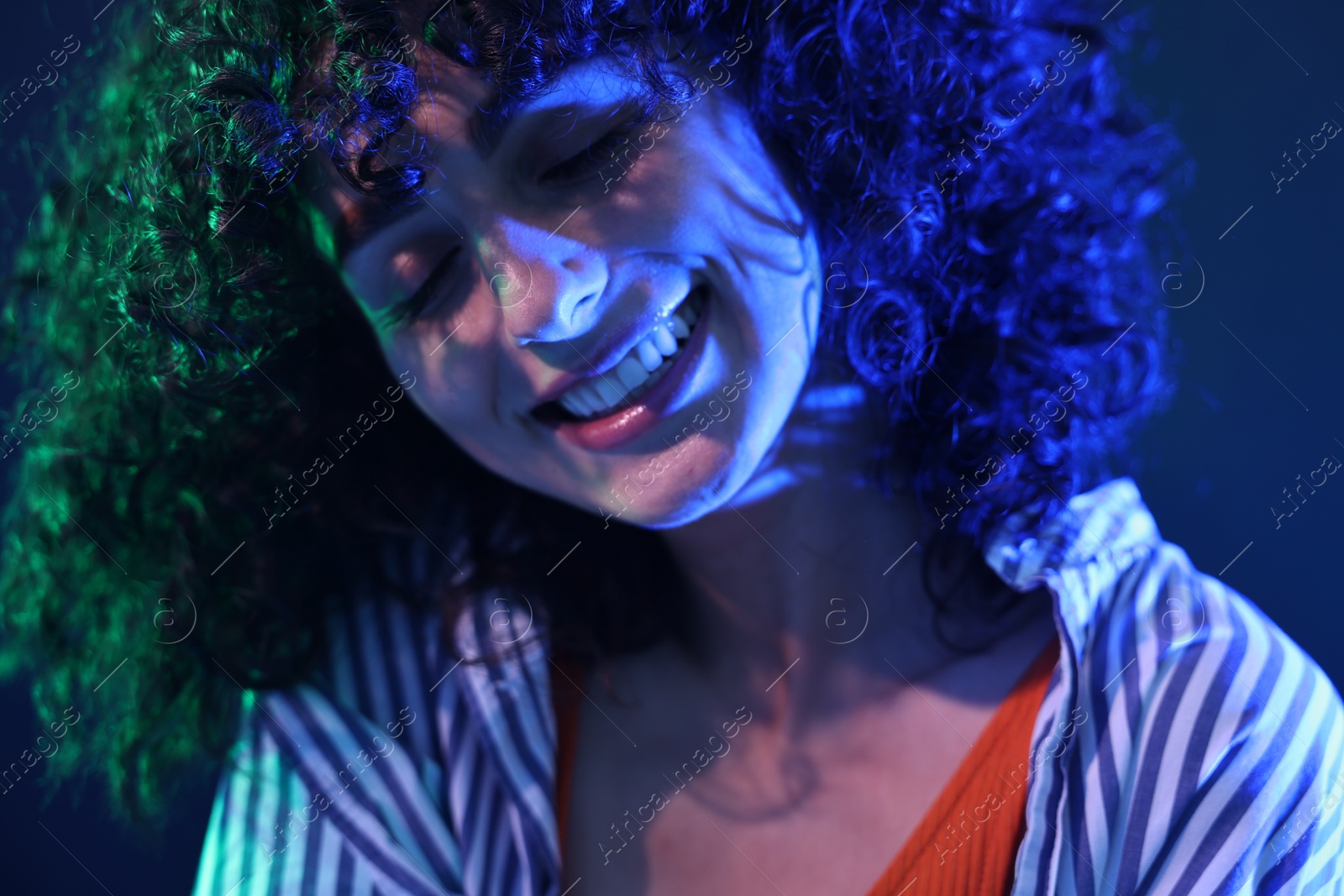 Photo of Beautiful young woman posing on color background in neon lights, closeup