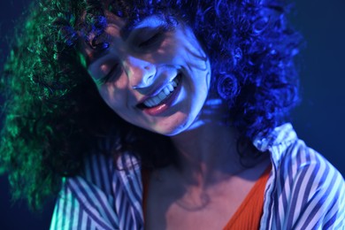 Photo of Beautiful young woman posing on color background in neon lights, closeup