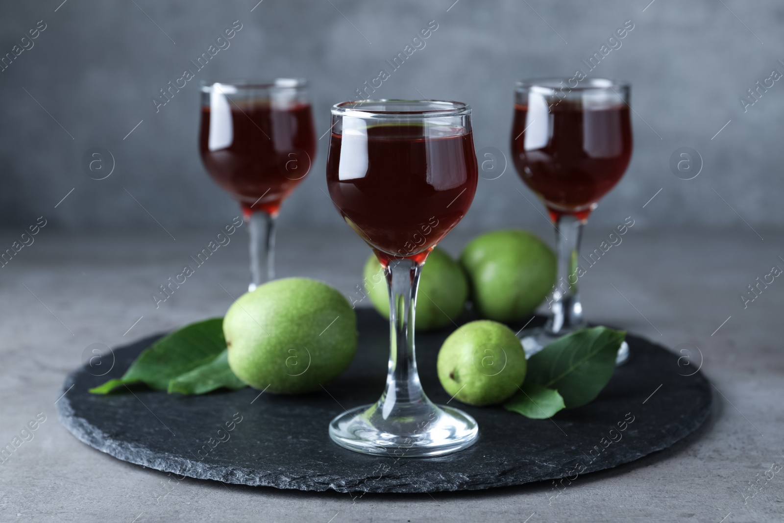 Photo of Delicious liqueur and green walnuts on grey table