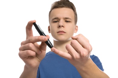 Photo of Teen boy using lancet pen on white background. Diabetes control