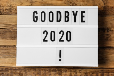 Lightbox with phrase Goodbye 2020! on wooden table, top view