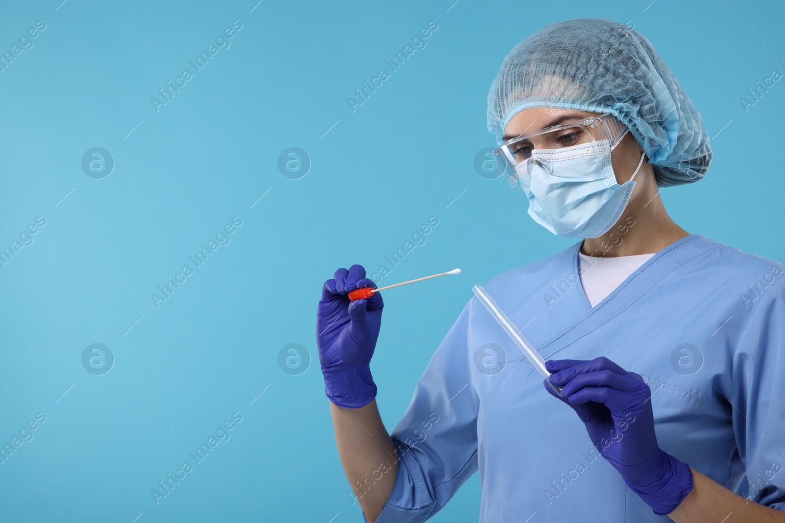 Photo of Laboratory testing. Doctor with cotton swab and tube on light blue background, space for text