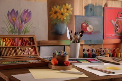 Photo of Artist's workplace with drawing, soft pastels and color pencils on table